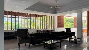 Un interior moderno con un sofá negro, sillones y una mesa de centro de vidrio.
