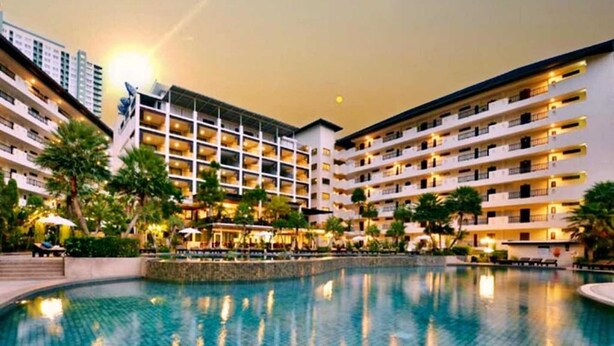 Un hotel con una piscina amplia, varios pisos y balcones.