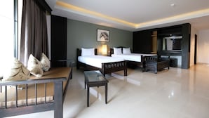 Una habitación de hotel con dos camas, un sofá, una mesa de centro de vidrio y una televisión.