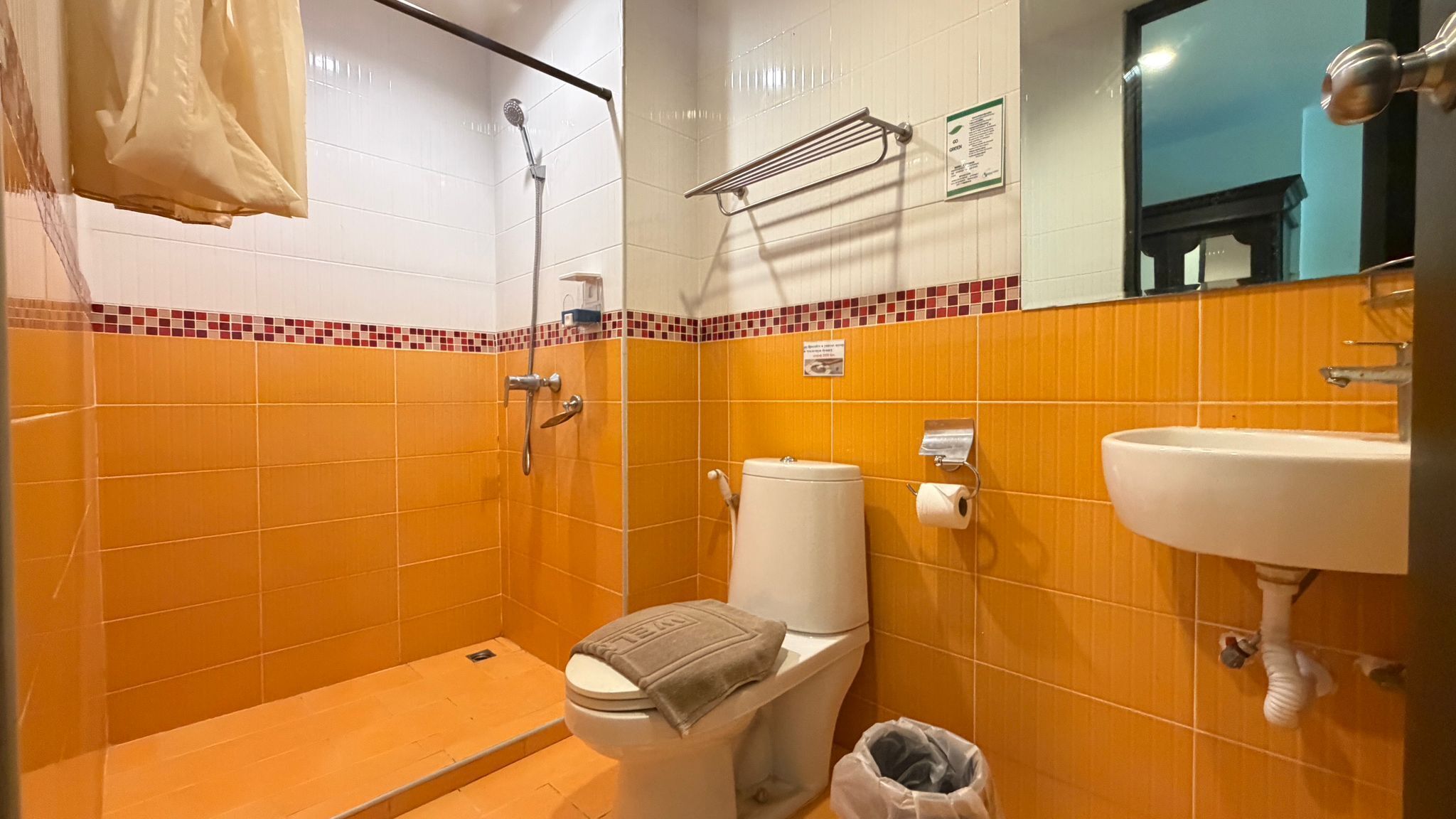 A bathroom with a shower, toilet, sink, and a towel rack.