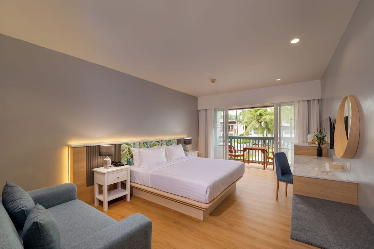 A modern bedroom with a large bed, bedside tables, a seating area, and a view of the outdoors.