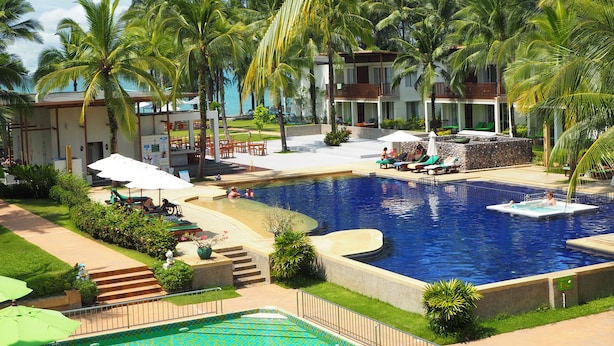 Ein Resort mit großem Pool, Palmen und Blick auf den Ozean.