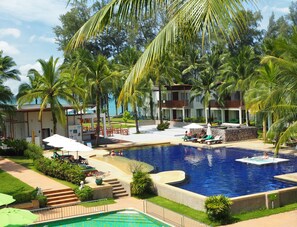 Un resort con una amplia piscina, palmeras y vista al océano.