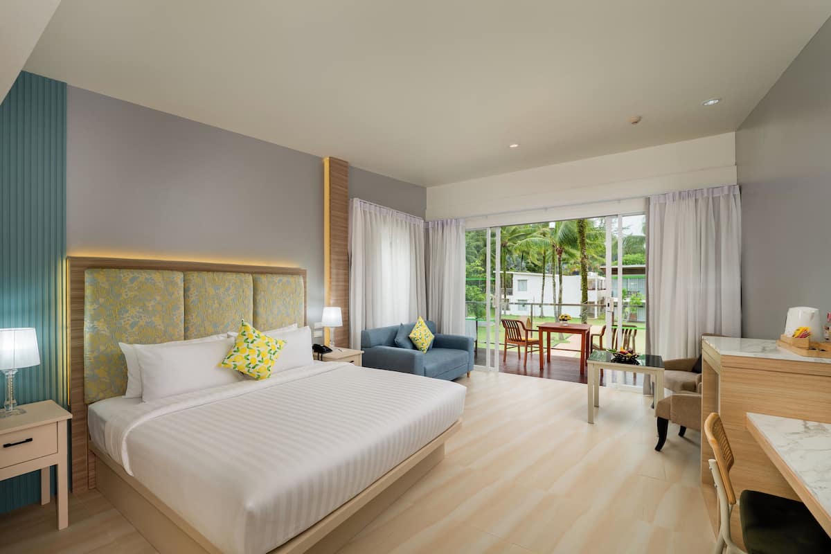 A modern hotel room with a large bed, a desk, and a view of the outdoors.