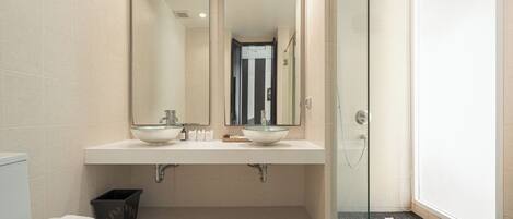 A modern bathroom with two sinks, a glass shower enclosure, and a toilet.