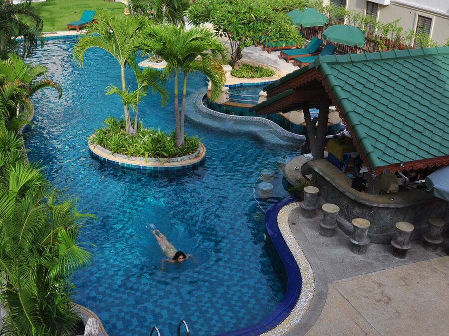 Una piscina al aire libre, sombrillas, sillones reclinables de piscina