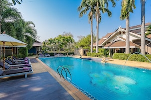 Una piscina al aire libre, sombrillas, sillones reclinables de piscina