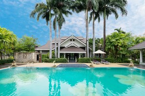 Una piscina al aire libre, sombrillas, sillones reclinables de piscina