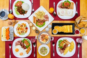 Un bufé de desayuno con diversos platos, como huevos, salchichas y ensaladas.