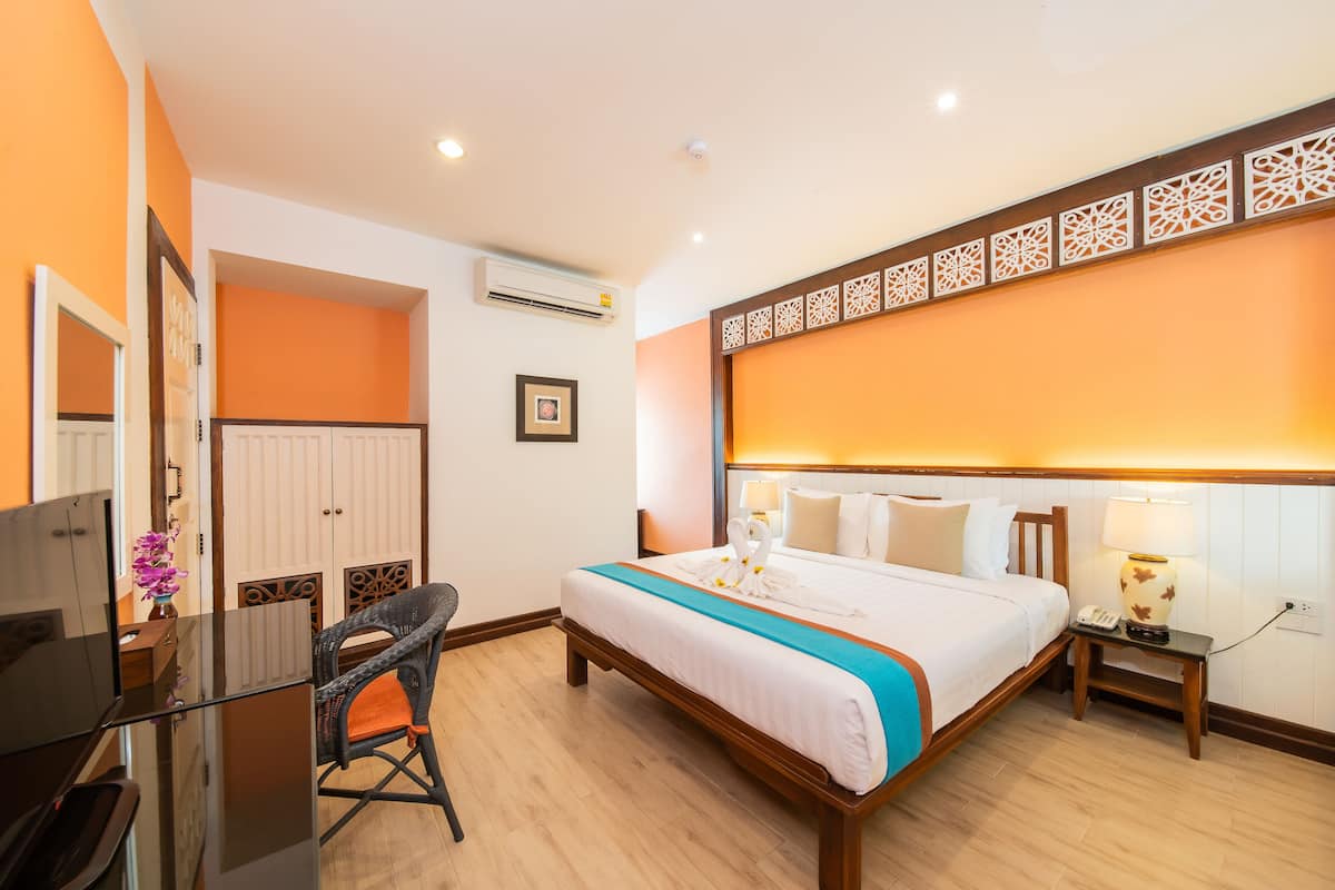 Una habitación de hotel con cama, mesita de noche, lámpara y un escritorio con silla.