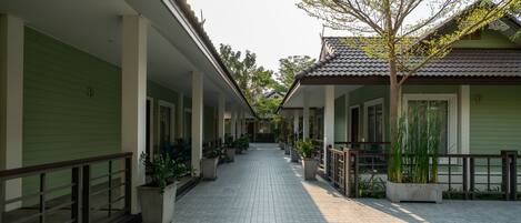 A corridor with tiled flooring, green walls, and potted plants.
