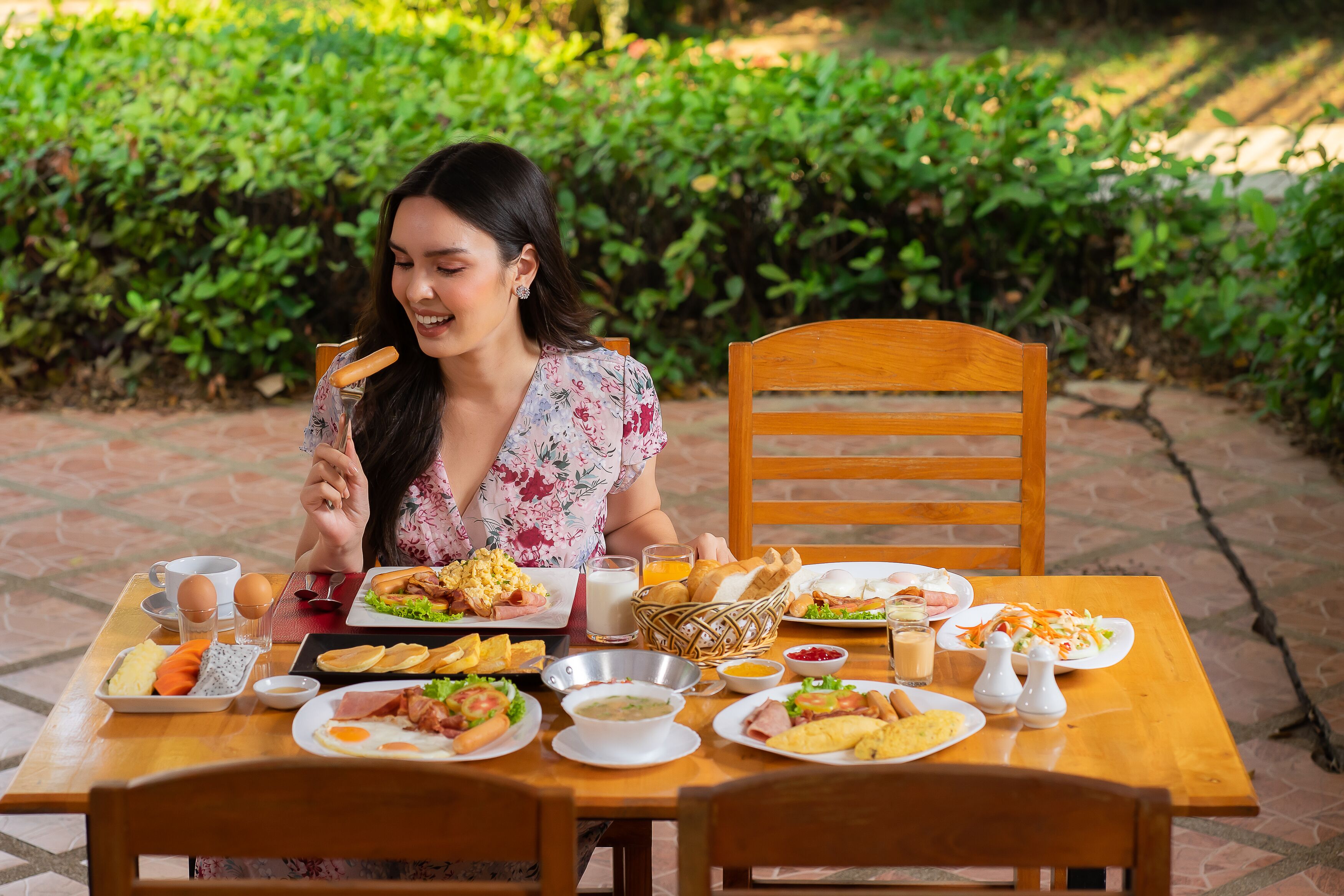 A dining table with various breakfast items and a person sitting at the table.