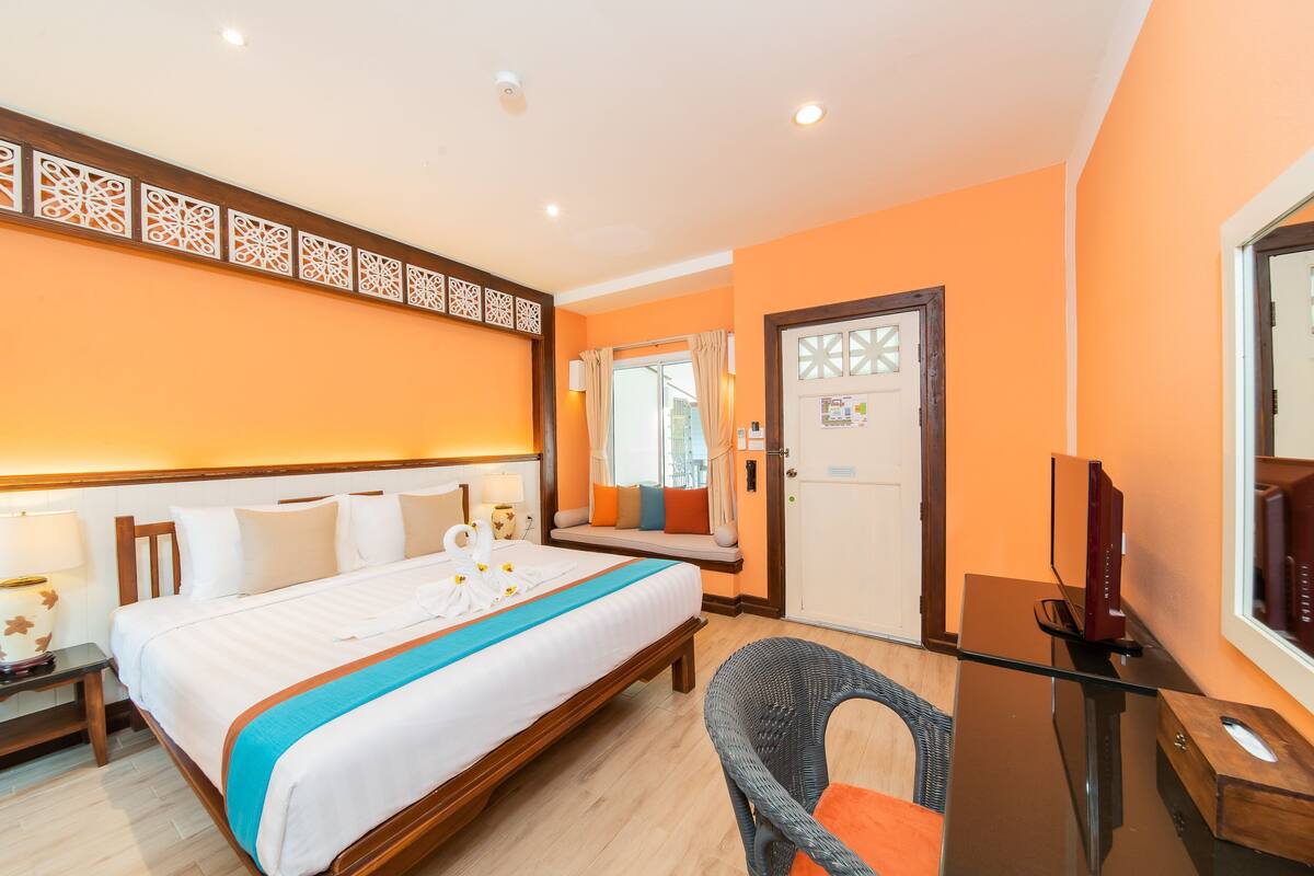 Una habitación de hotel con una cama, un escritorio, una silla, un televisor y una puerta.
