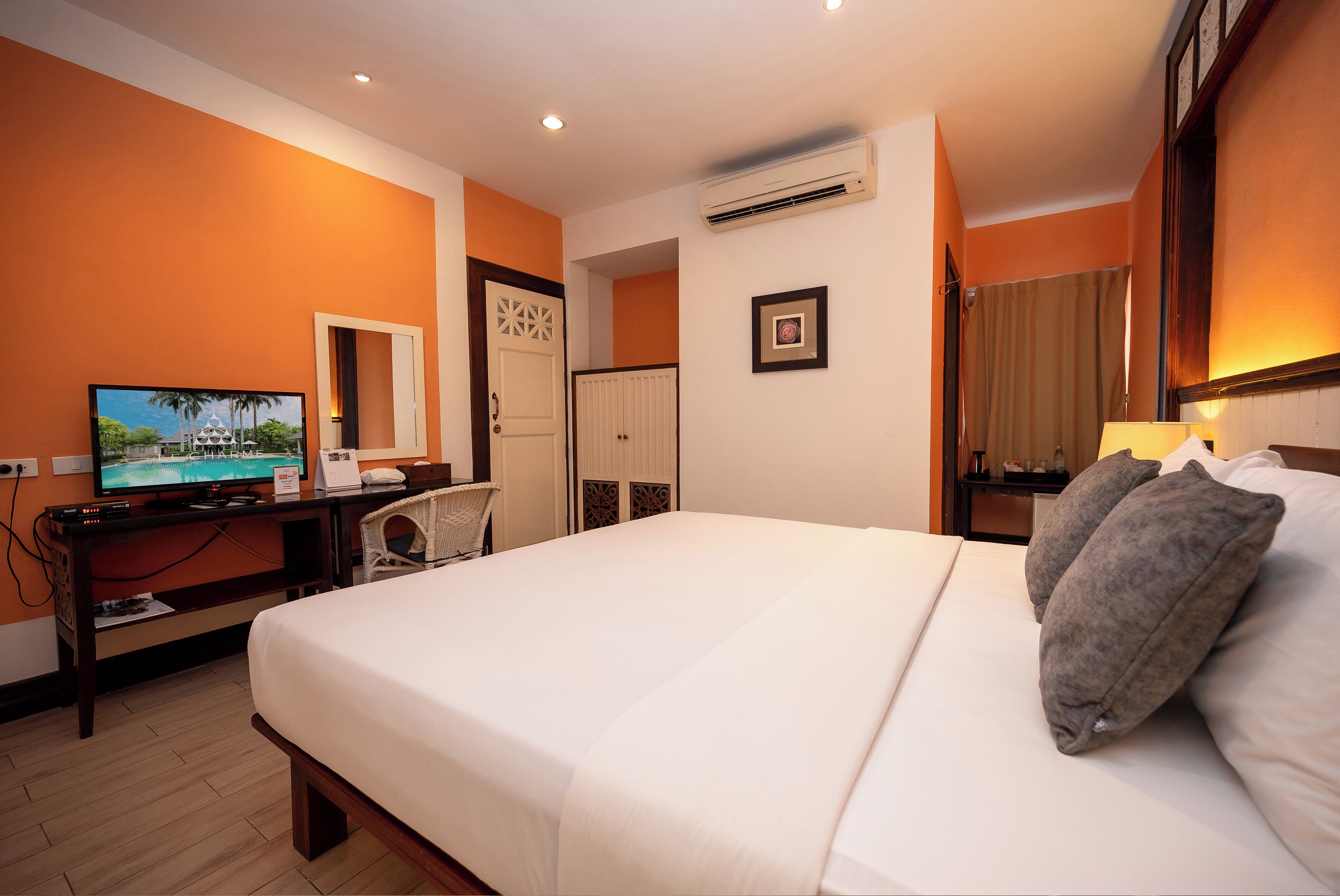 Una camera d'hotel con un letto, una scrivania con televisore, un armadio e un condizionatore d'aria.