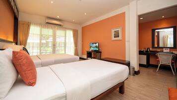 A hotel room with two beds, a desk, a television, and a bathroom visible through an open door.