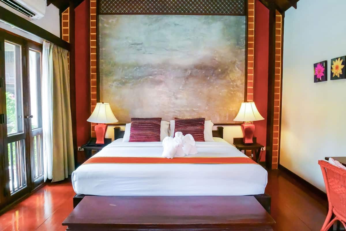 A hotel room with a large bed, two bedside tables with lamps, a bench, and a large abstract painting on the wall.