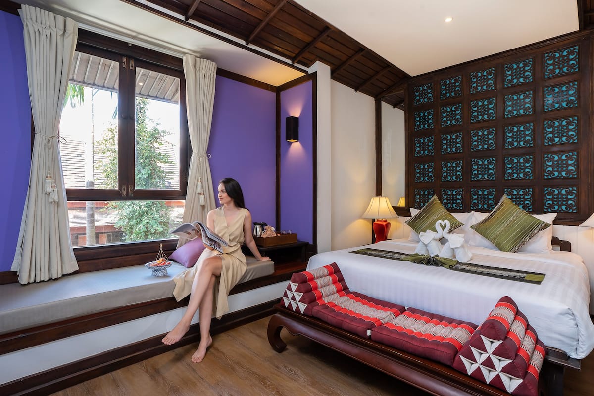 A room with a bed, a sofa, a window with curtains, and a wall with decorative panels.
