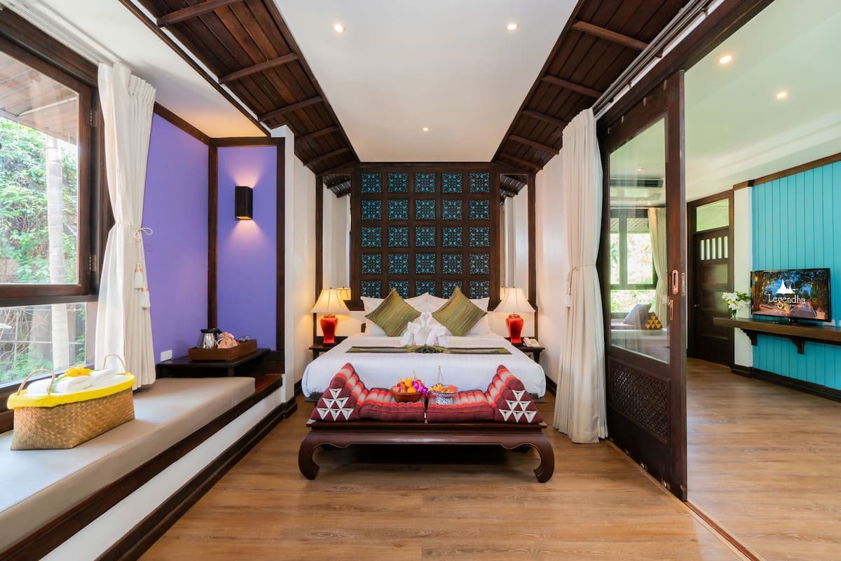 A bedroom with a large bed, bedside tables, a TV, and a window with curtains.