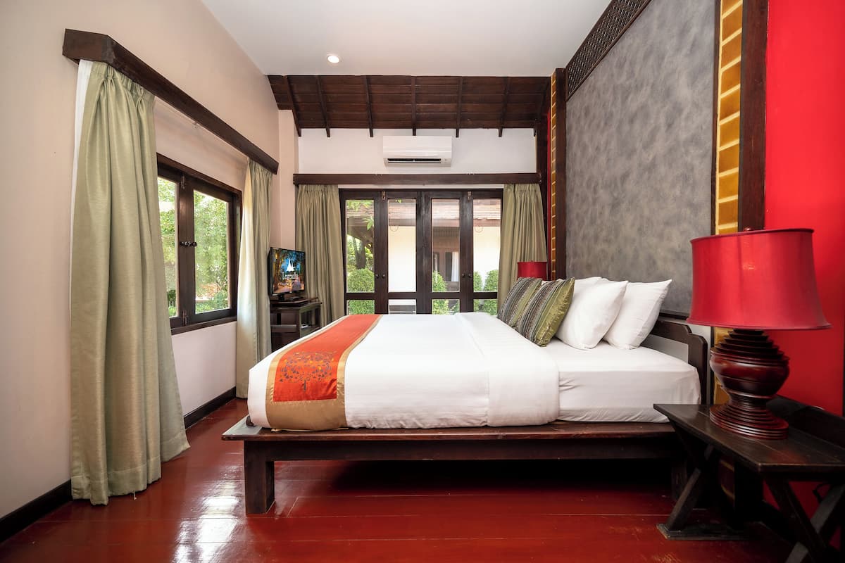 A bedroom with a bed, a red lamp, and a window with curtains.