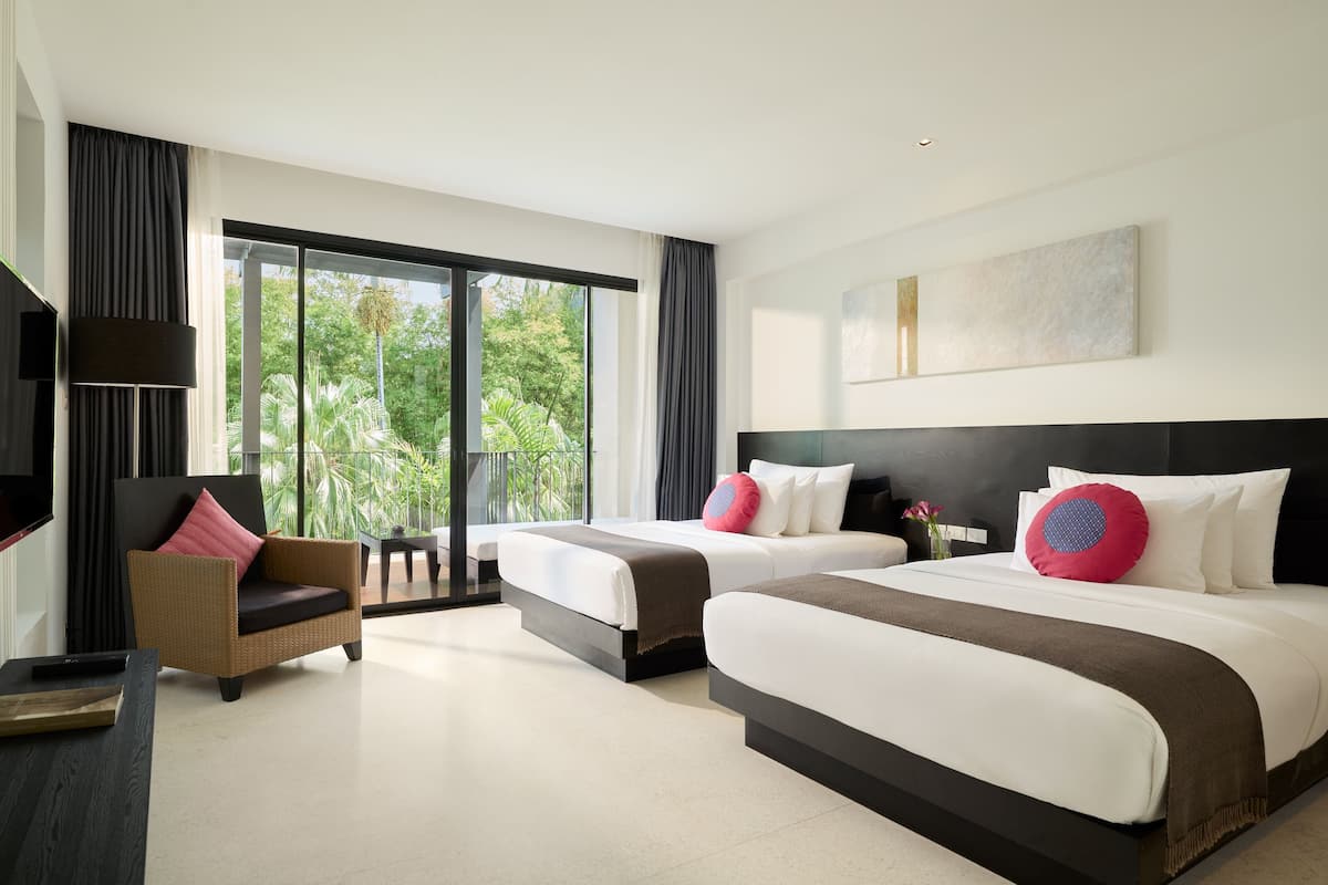 Habitación de hotel moderna con dos camas, un sofá, un televisor y grandes ventanales con vistas a zonas verdes.