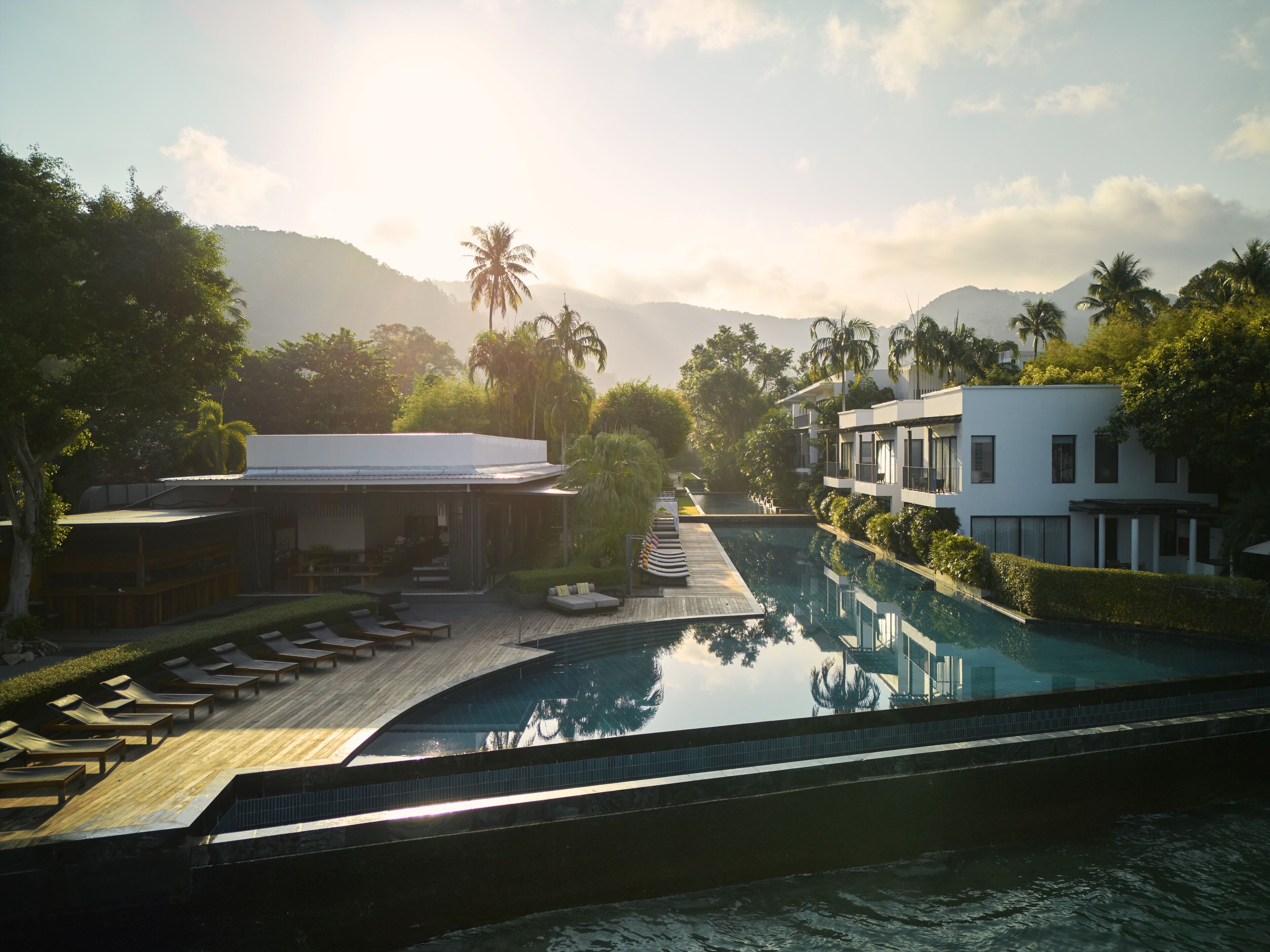 A resort with a swimming pool, lounge chairs, and a restaurant with outdoor seating.