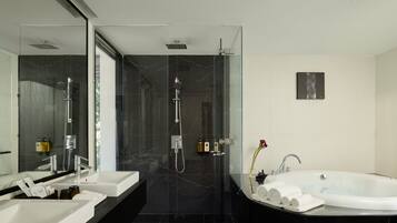 A modern bathroom with a glass-enclosed shower, a large bathtub, and dual sinks.
