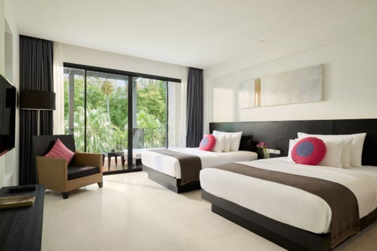 A modern hotel room with two beds, a sofa, a TV, and large windows.