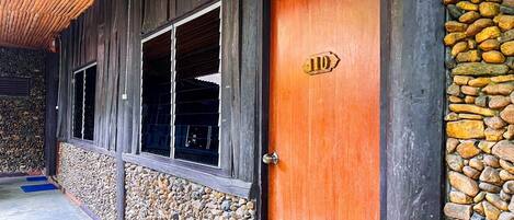 A wooden building with a stone wall and a wooden door marked with the number 110.