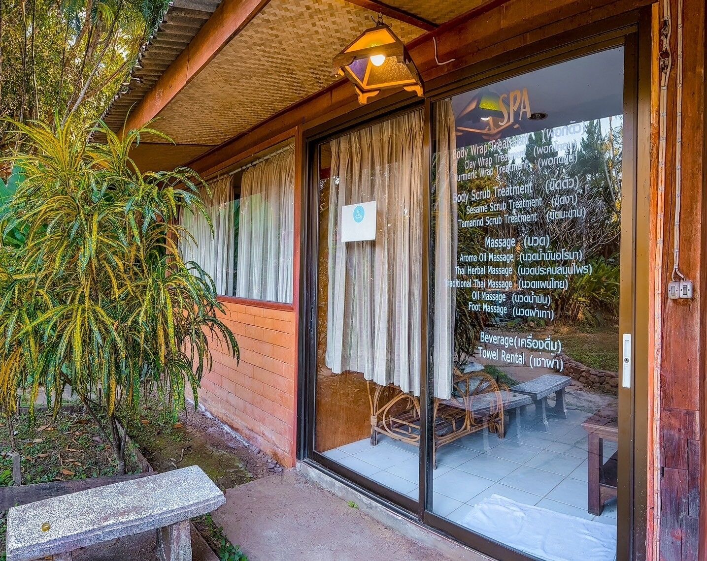 A spa with a glass door, wooden exterior, and a sign listing services like massages and treatments.