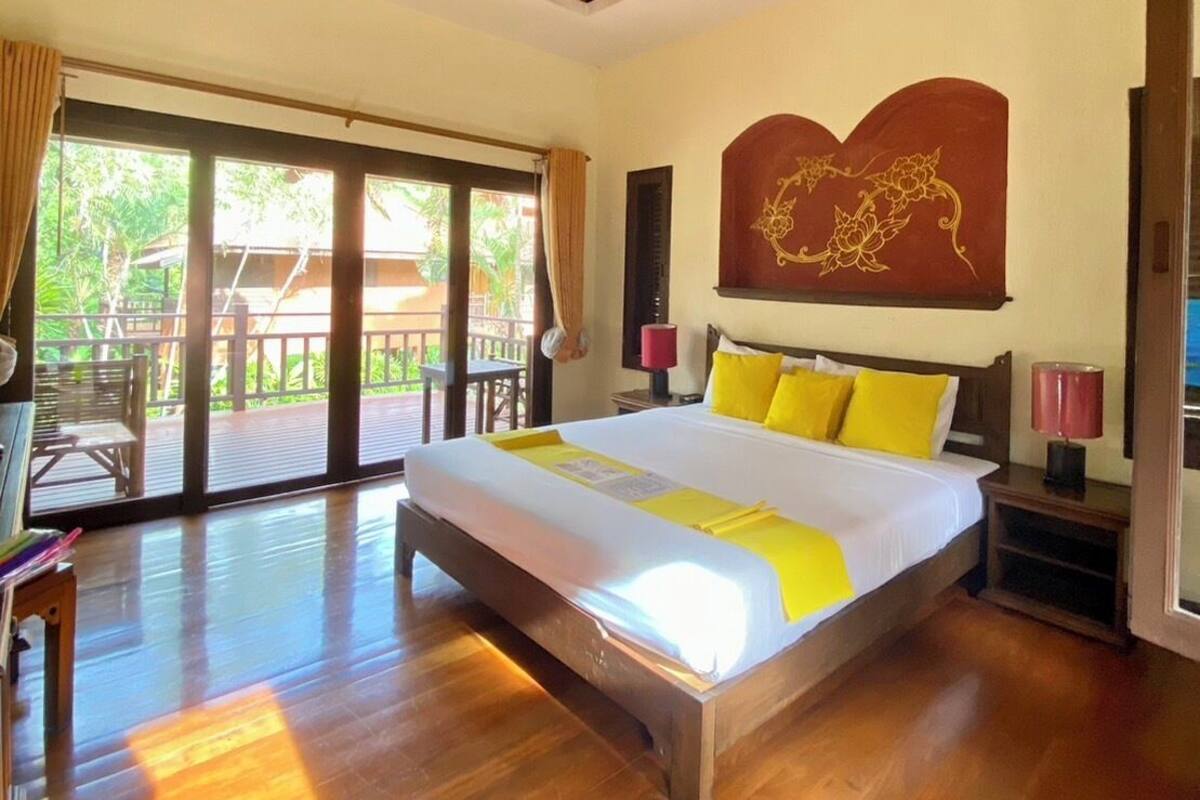 A spacious bedroom with a large bed, a ceiling fan, and a view of the outdoors through large sliding doors.