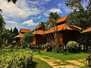 A traditional-style building with multiple rooms, surrounded by lush greenery and a clear sky. - Pai Hotsprings Spa Resort (Pai)