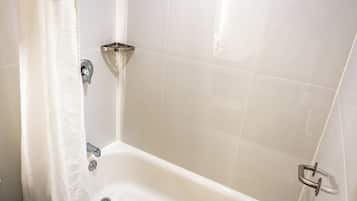 Un baño con bañera, cortina de ducha y baranda.