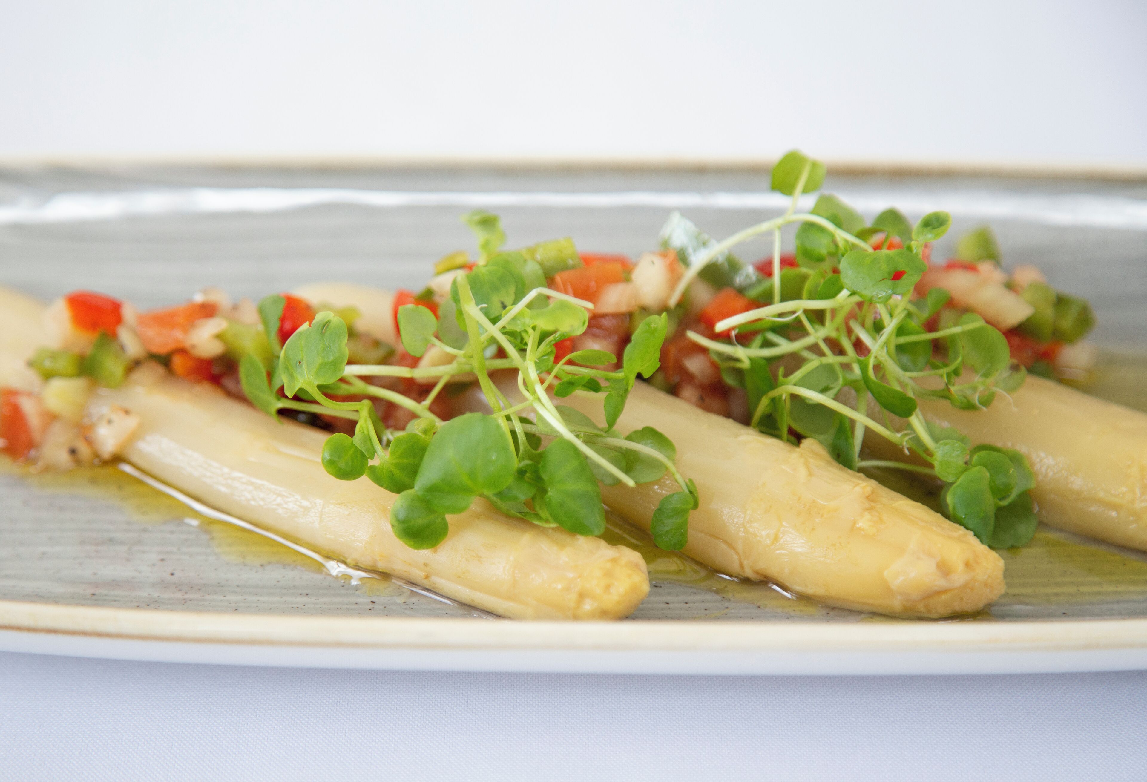 Une assiette de nourriture comprenant des asperges et une garniture à base de tomates.