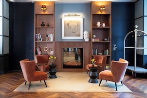 A modern living room with a fireplace, bookshelves, and two armchairs.