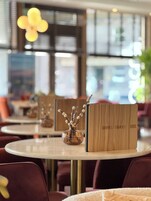Ein moderner Essbereich mit runden Tischen, einem Menüständer und einer dekorativen Vase mit Zweigen.