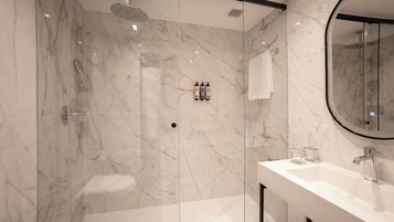 Ein modernes Badezimmer mit einer Duschkabine, einer Toilette und einem Waschbecken mit Spiegel.
