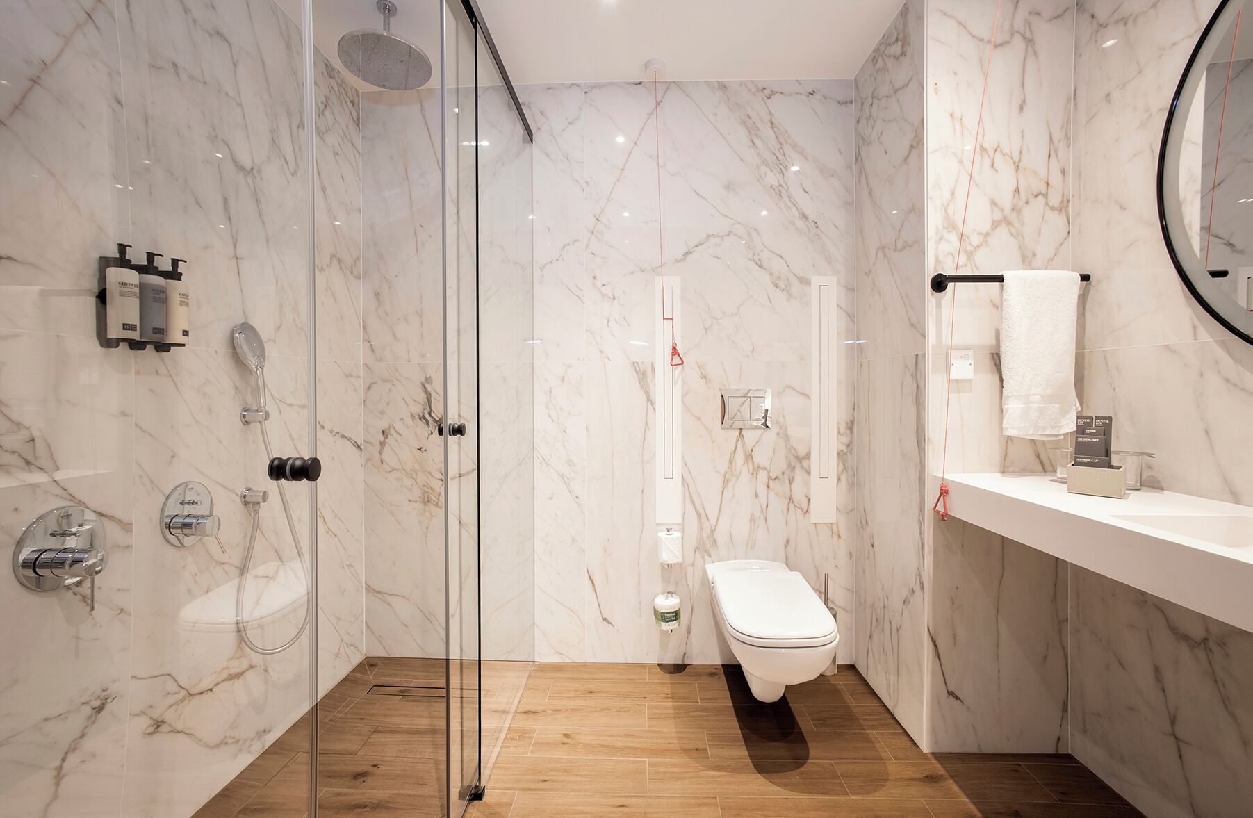 Een moderne badkamer met een douchecabine van glas, een toilet en een wastafel met spiegel.