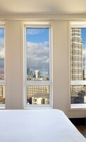 A room with a large window offering a view of a cityscape, including modern buildings and a crane.