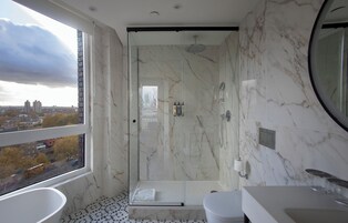 A modern bathroom with a glass-enclosed shower, a large bathtub, and a toilet.
