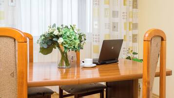 Une table en bois avec un ordinateur portable, une tasse blanche et un vase rempli de fleurs.