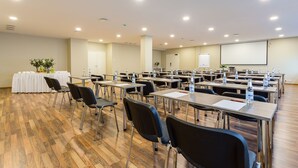 A conference room with multiple tables and chairs, equipped with water bottles and a projector screen. - Hotel Dzingel (Tallinn)