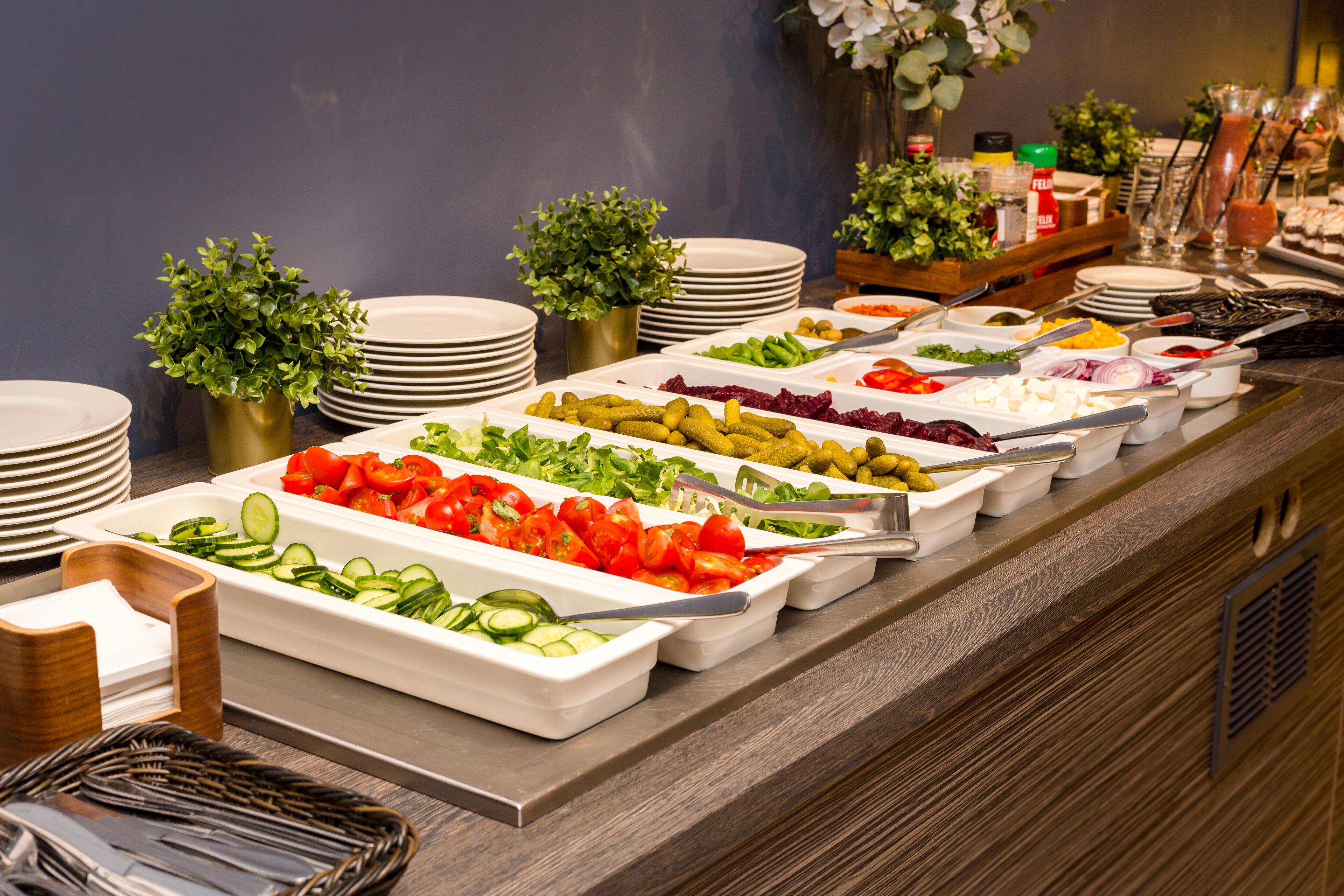 A buffet with various food options, including salads, vegetables, and dips.