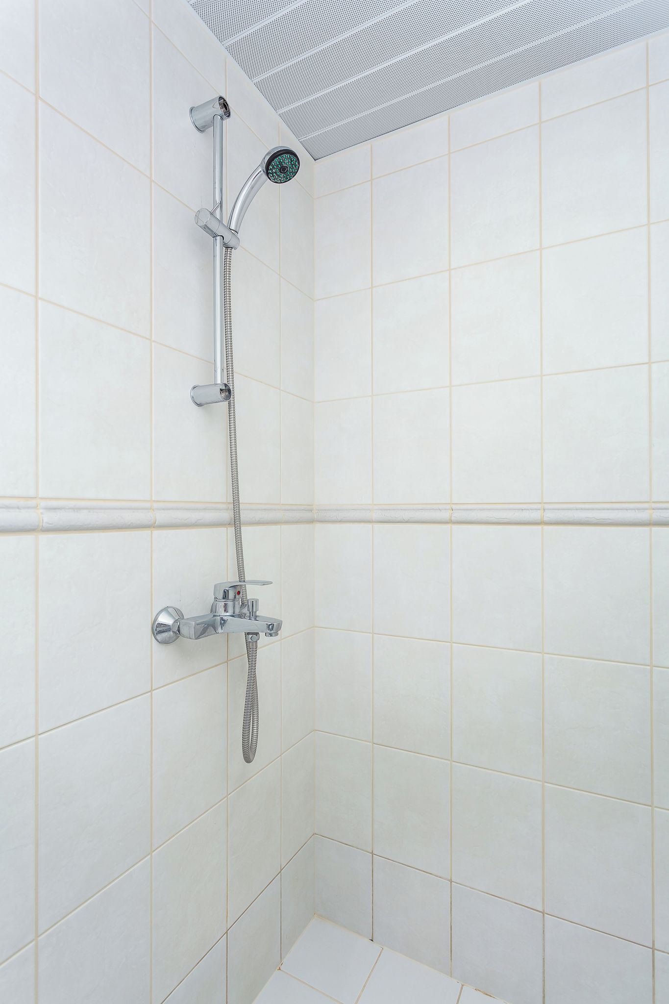 Une douche équipée d’un pommeau de douche à main, d’un robinet mural et d’un flexible.
