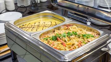 Ein Buffetsystem mit Pasta und einem cremigen Gericht, umgeben von gestapelten Tellern und Schüsseln.
