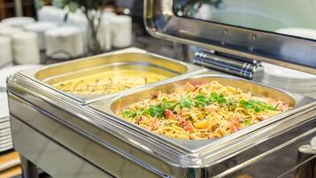 A buffet with pasta dishes, including one with green herbs.