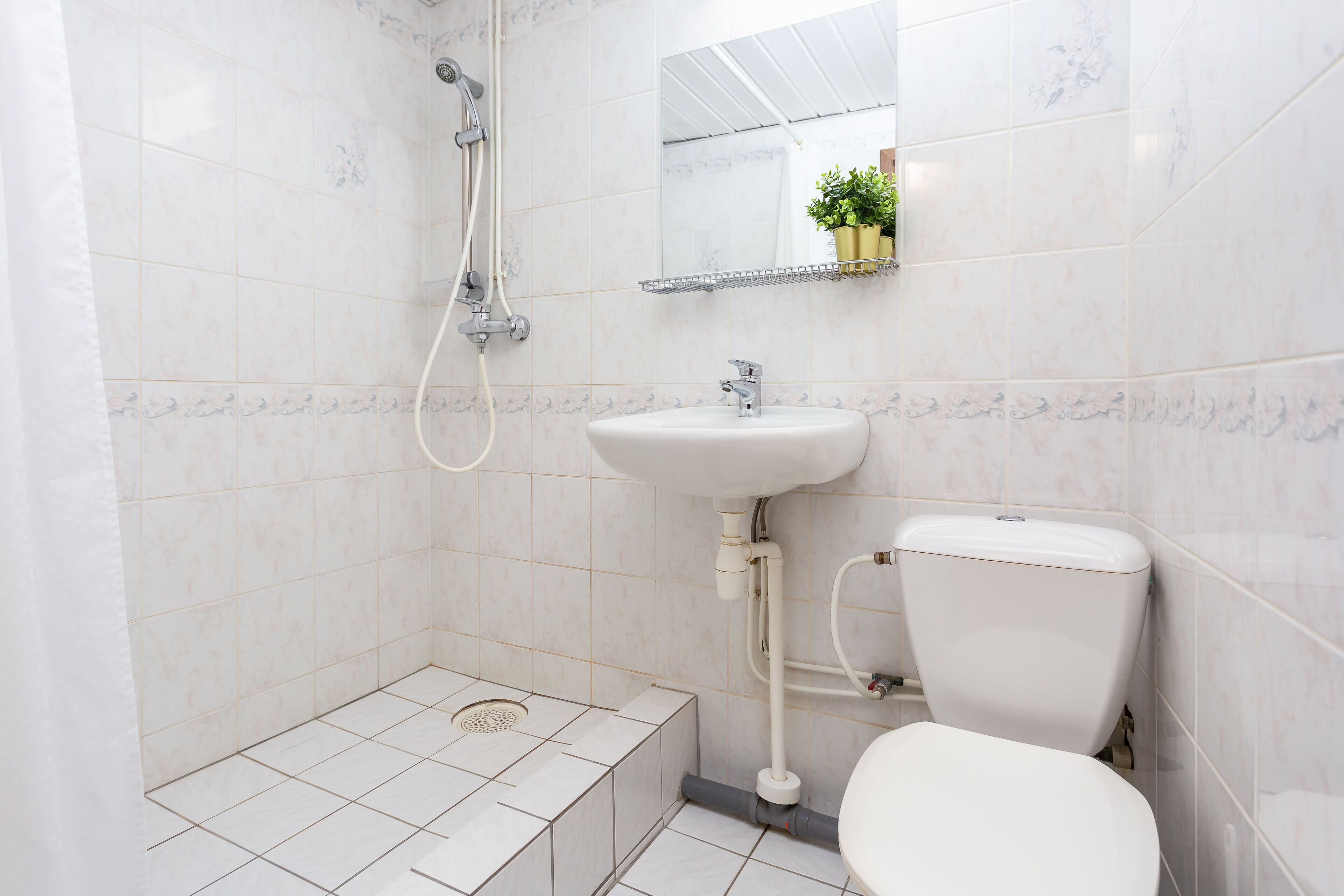 Une salle de bain avec un lavabo, des toilettes et une douche, le tout de couleur blanche.