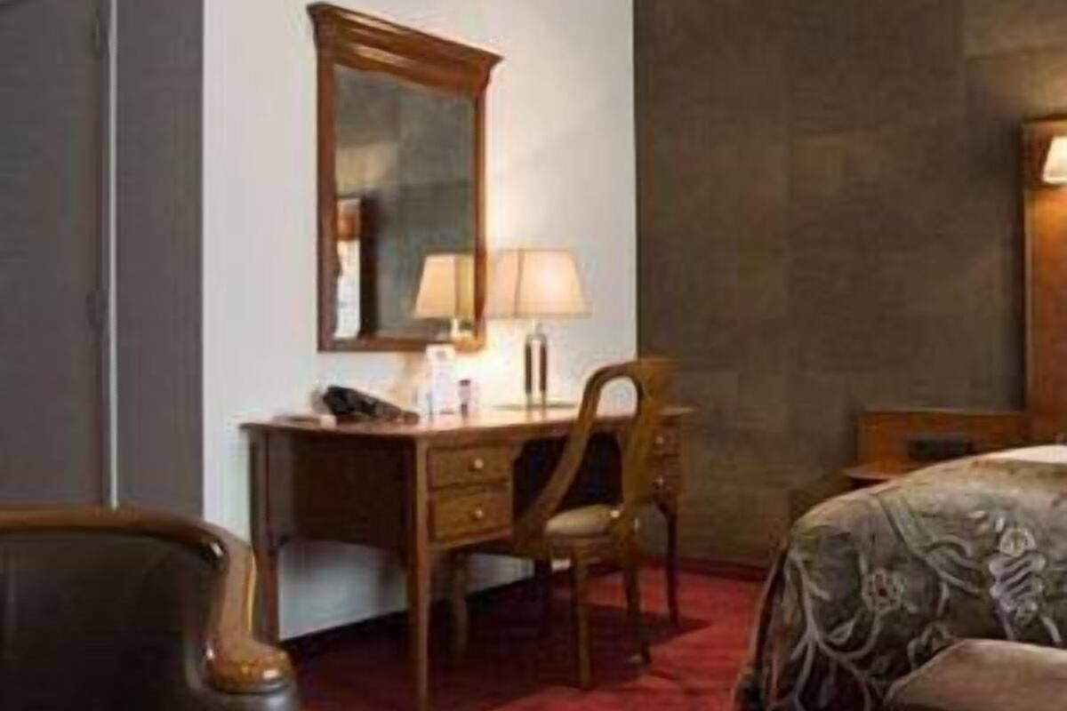 Une chambre d’hôtel équipée d’un bureau, d’une chaise et d’un lit recouvert d’une couvre-lit à motifs floraux.