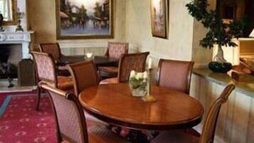 Un coin repas avec une table ronde et six chaises, une cheminée et un grand tableau au mur.