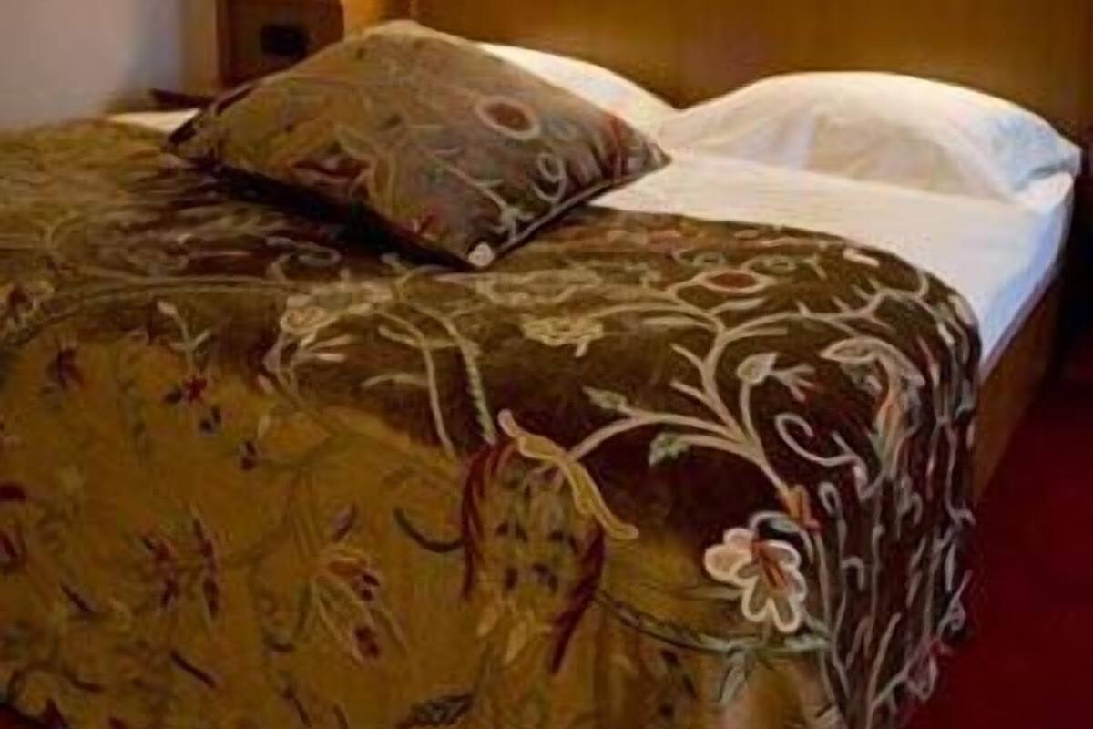 Un lit avec une couvre-lit à motifs floraux et deux oreillers, une tête de lit en bois et des lampes de chevet.