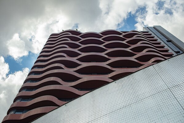Un edificio alto con una fachada ondulada distintiva y una sección con patrón de cuadrícula.